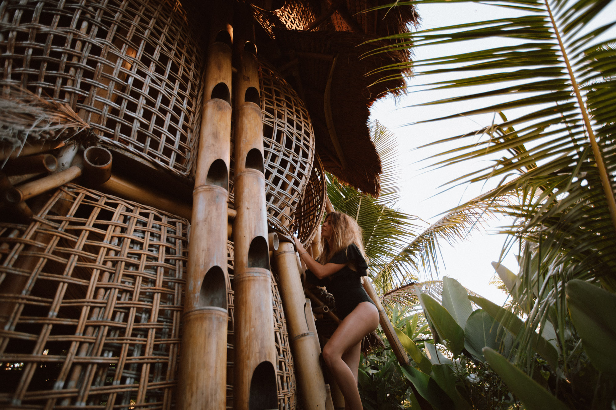 girl climbing a tree bamboo house in the jungle in ubud bali